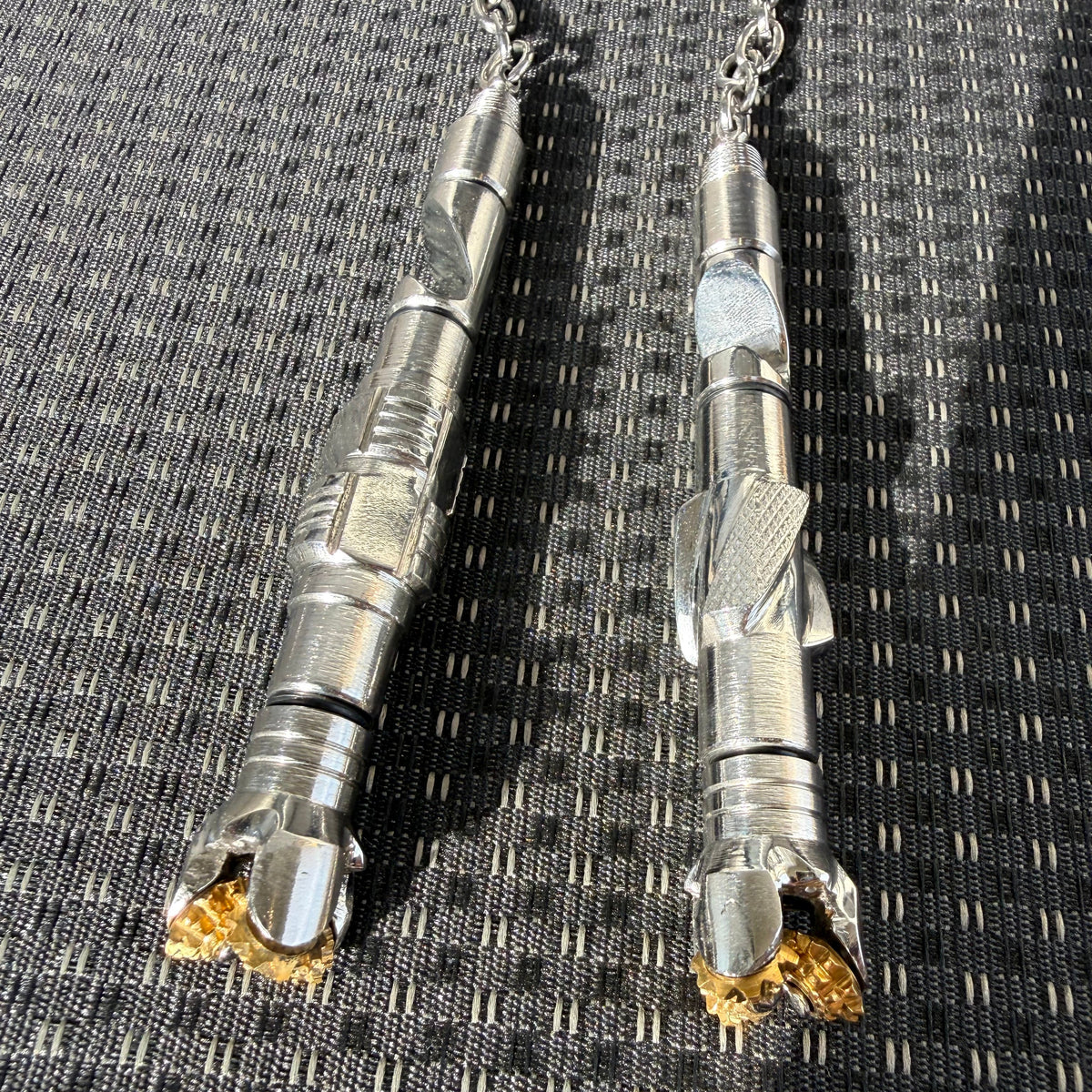 Two metal drill bits on a textured black and gray surface
